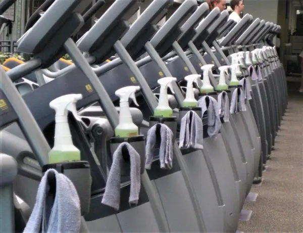 A row of STR-201 - Sanitation Stations in a gym with towels on them.